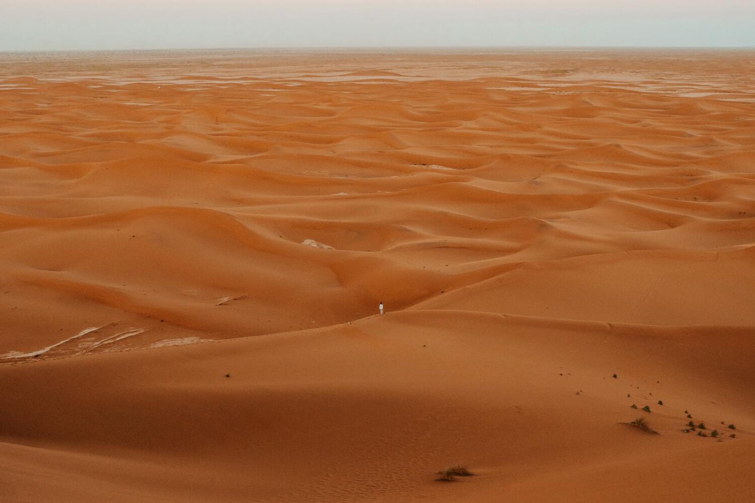 A mesmerizing aerial shot capturing the vast and golden sand dunes of the Sahara Desert in Morocco.